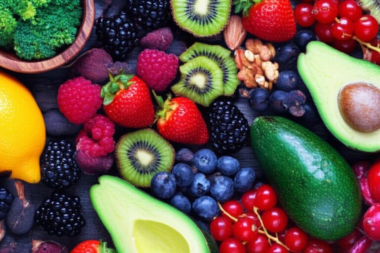 Variedad de frutas y verduras ricas en antioxidantes, incluyendo fresas, kiwis, aguacates y arándanos.