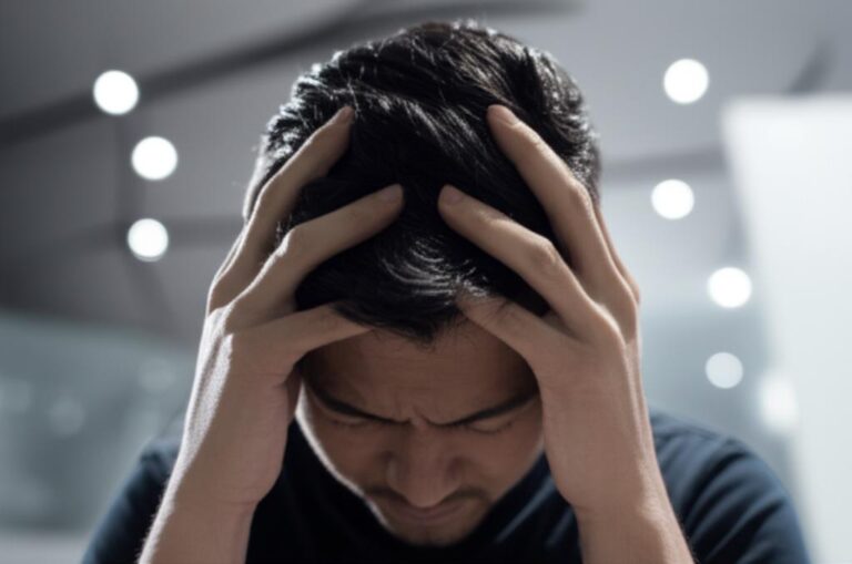 Persona con las manos en la cabeza, representando estrés y presión arterial alta.