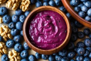 Bowl of acai berry smoothie surrounded by blueberries and walnuts