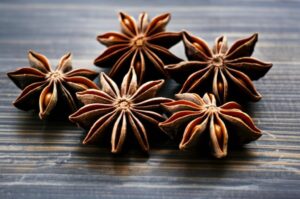 Fotografía de cinco anises estrellados sobre superficie de madera.