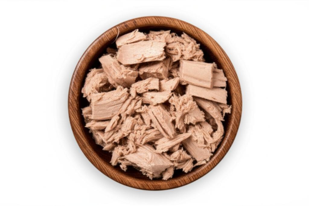 Atún enlatado desmenuzado en un cuenco de madera sobre fondo blanco, ideal para contenido nutricional y recetas.