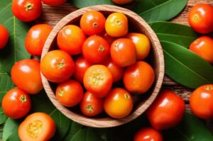Camu camu fresco en un tazón de madera rodeado de hojas verdes, mostrando la fruta para información nutricional.