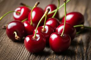 Grupo de cerezas rojas brillantes sobre una superficie de madera, destacando su frescura y atractivo visual.