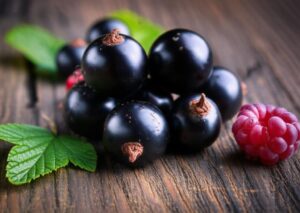 Primer plano de grosellas negras frescas con hojas verdes sobre fondo de madera.