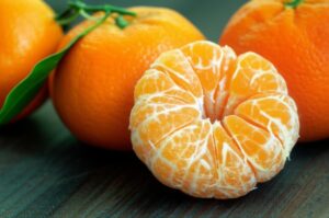 Mandarina pelada junto a mandarinas enteras
