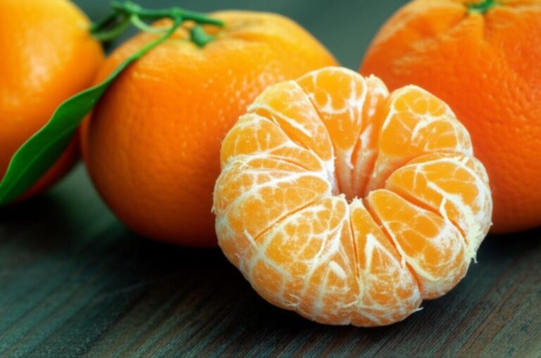 Mandarina pelada junto a mandarinas enteras