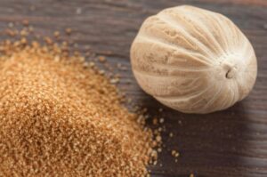Nuez moscada entera y molida sobre superficie de madera