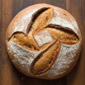 Pan de masa madre redondo y crujiente sobre fondo de madera, ideal para información nutricional.