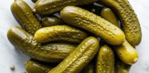 Fotografía cenital de pepinillos fermentados en primer plano, resaltando su textura y color para información nutricional.