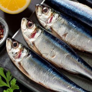 Imagen de primer plano de sardinas frescas con limón y perejil, listas para cocinar.