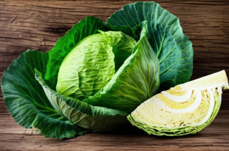 Col verde entera y una porción de col cortada sobre tabla de madera, para información nutricional y recetas.