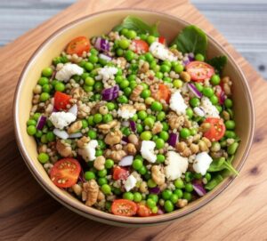 Ensalada de quinoa con guisantes, tomates cherry, cebolla morada y queso feta en un tazón.