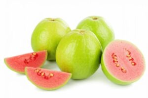 Guayabas enteras y en rodajas mostrando su pulpa rosada y semillas, resaltando los beneficios nutricionales de la fruta.
